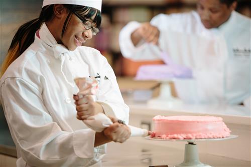 A student frosts a cake.