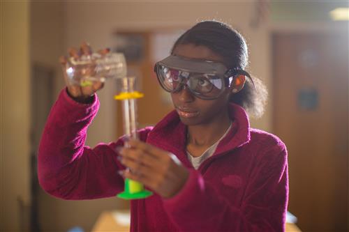 Student pours liquid into a beaker.