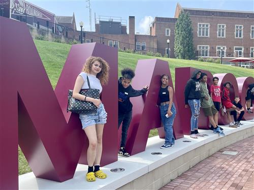 Community Builders students standing in front of Roanoke College Maroons sign